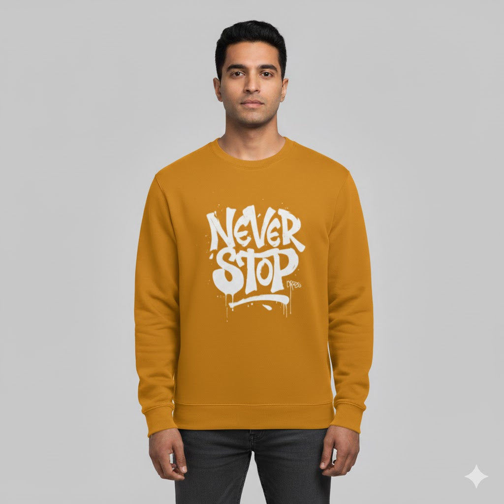 Man wearing a mustard yellow sweatshirt with 'Never Stop' text on a gray background